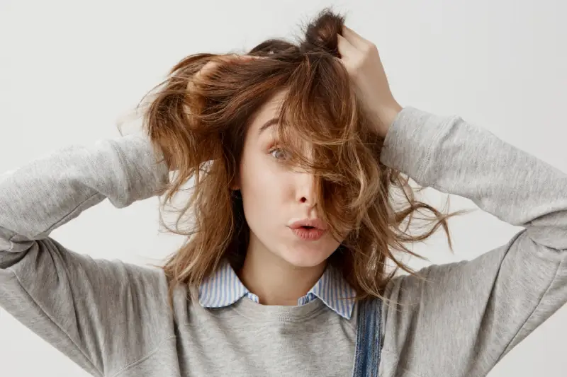 Mujer tocándose el pelo dañado